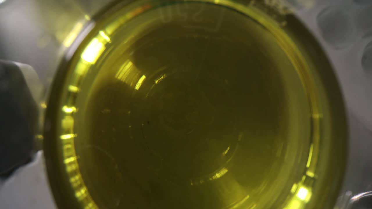 Top-down view of yellow liquid in a glass beaker