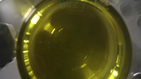 top-down view of yellow liquid in a glass beaker