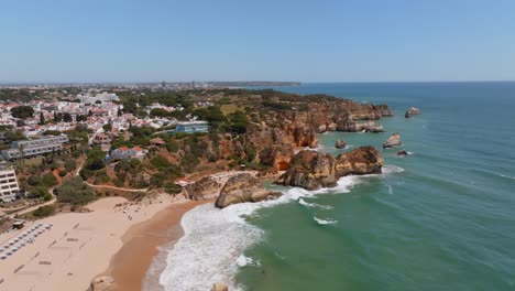 Toma-Aérea-Estática-De-Praia-Dos-Três-Irmaos-Y-La-Ciudad-Costera-De-Portimao,-Portugal