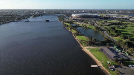 drone volando sobre el río swan con el puente matagarup y el estadio optus en el fondo, ciudad de perth en australia occidental