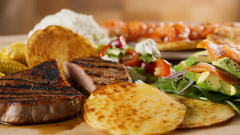 a delicious and varied food spread featuring grilled meat, salmon avocado salad, and pancakes
