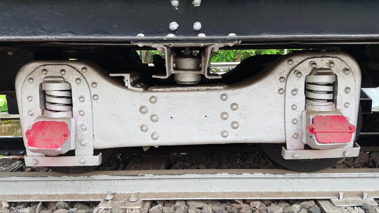 Primo piano con carrellata da sinistra a destra del gruppo sospensione e bilanciere sotto una locomotiva a vapore conservata. Solo per uso editoriale