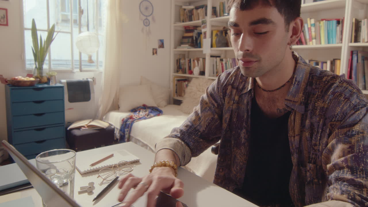 Young Man Opening Laptop and Typing at Desk in Domestic Room