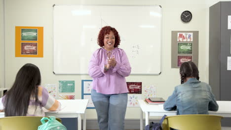 female teacher engaging with multiracial students in classroom, boy raising hand, at school