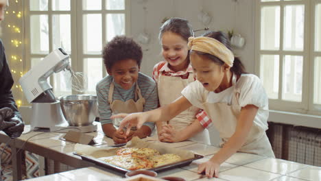 niños felices disfrutando de pizza recién horneada en la clase de cocina