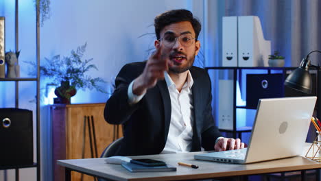 Business-man-working-on-office-laptop-pointing-to-camera-looking-with-happy-expression-making-choice