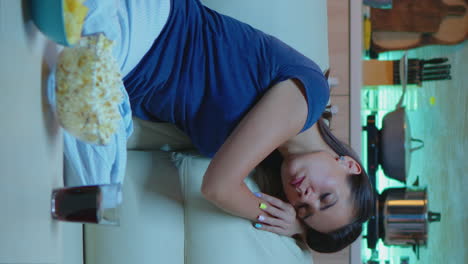 vertical video: woman sleeping on a sofa in front of tv