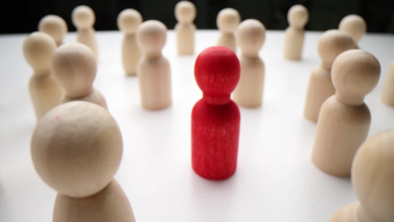 One Red Figure Standing Out in a Crowd of Wooden People