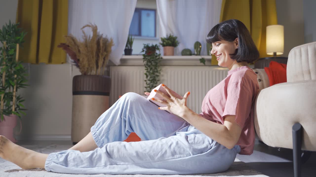 집에서 선물 상자를 열고 있는 여성은 흥분하고 행복합니다.