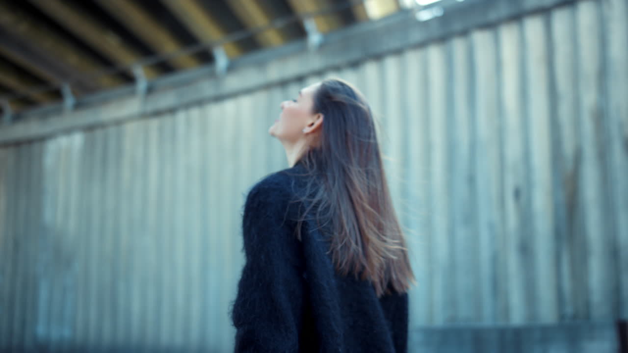 mujer joven de pie en la calle de la ciudad. chica bonita agitando el cabello en el clima ventoso