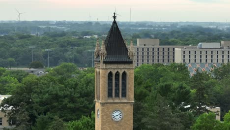 iconic campanile tower at iowa state university, set against lush greenery, with distant buildings and wind turbines