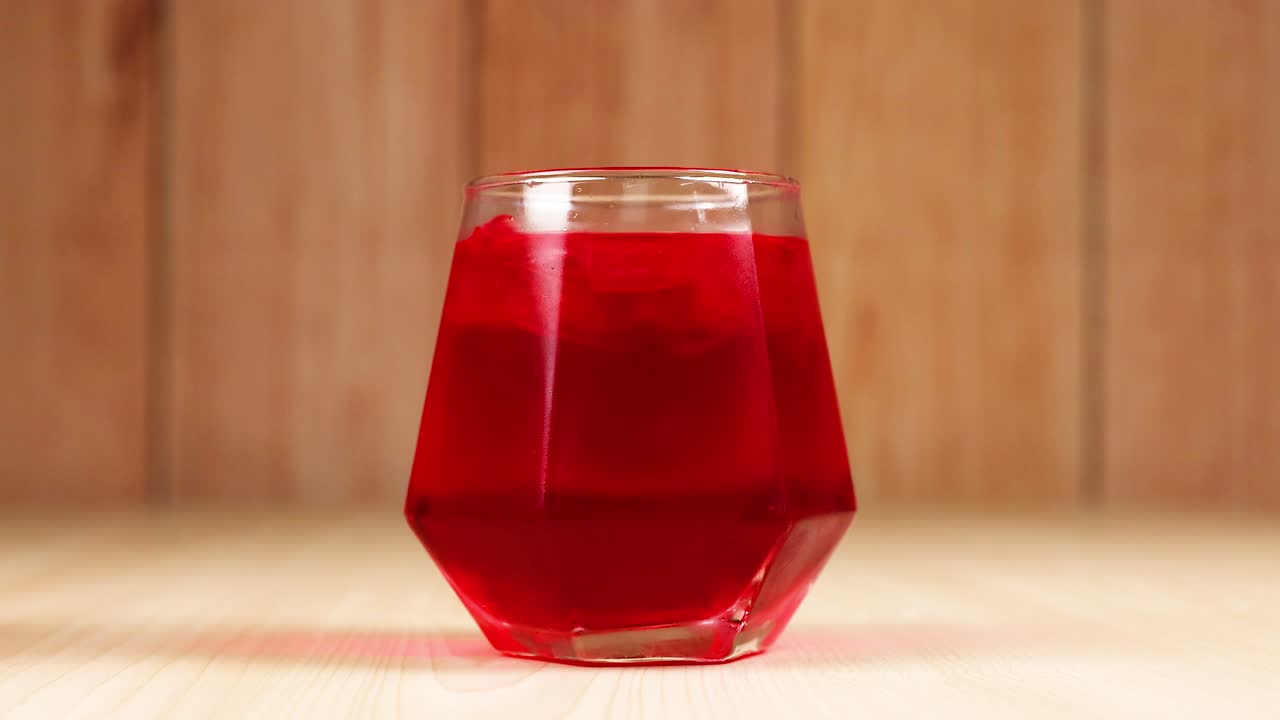 la mano alcanza y sostiene la bebida roja