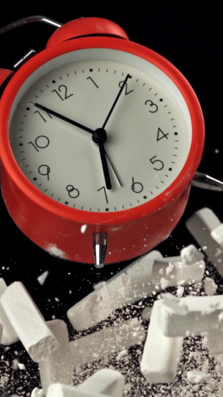 Sveglia rossa con frammenti di gesso che cadono al rallentatore