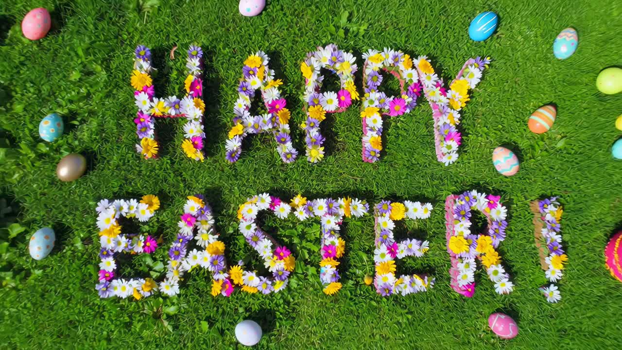 Top-down video of 'Happy Easter' spelled with flowers on grass, surrounded by colorful eggs