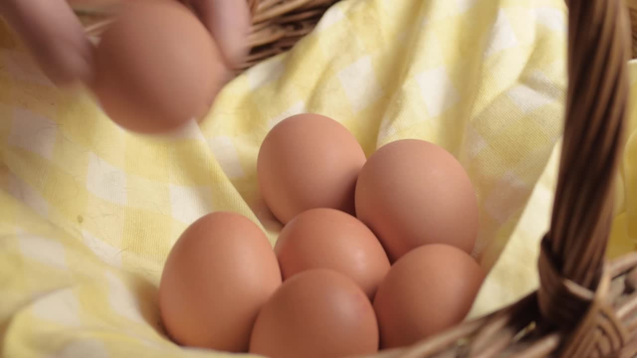Hand getting fresh brown eggs out of a woven basket