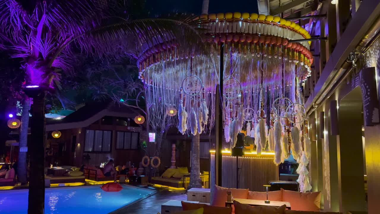 Colorful lights and decorations illuminate a lively beach club in Phuket, Thailand, creating a festive and energetic atmosphere