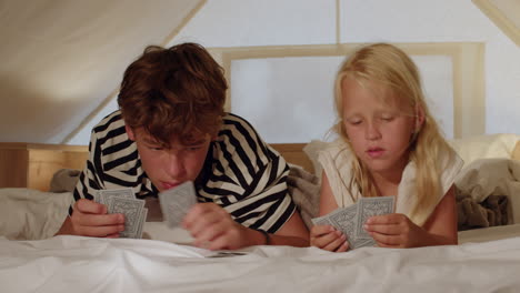 siblings playing cards in a tent