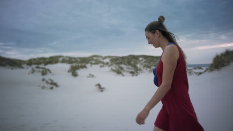 Mujer-Joven-Camina-En-Una-Playa-De-Arena-Blanca-Con-Un-Vestido-Rojo