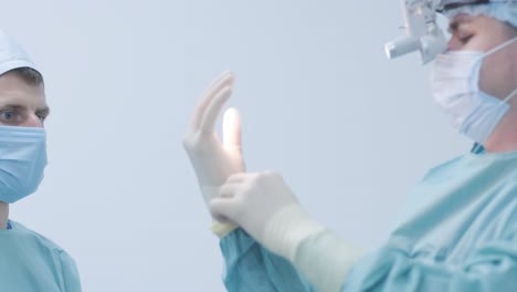 enfermera ayudando al cirujano a ponerse guantes estériles antes de la cirugía