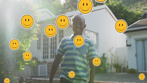 Animation-of-smiley-faces-over-happy-african-american-boy-in-garden