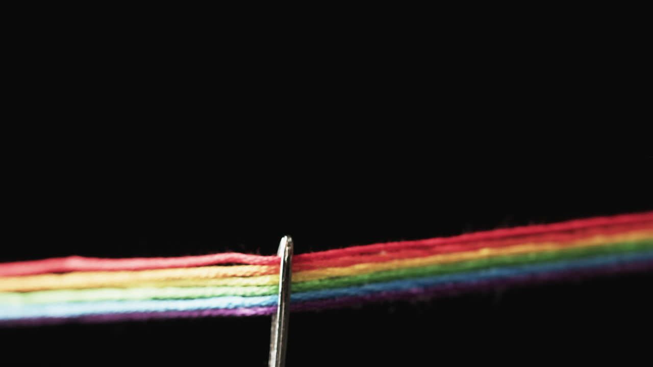 video de micro de hilos de color arco iris que pasan a través de la aguja con espacio de copia en fondo negro