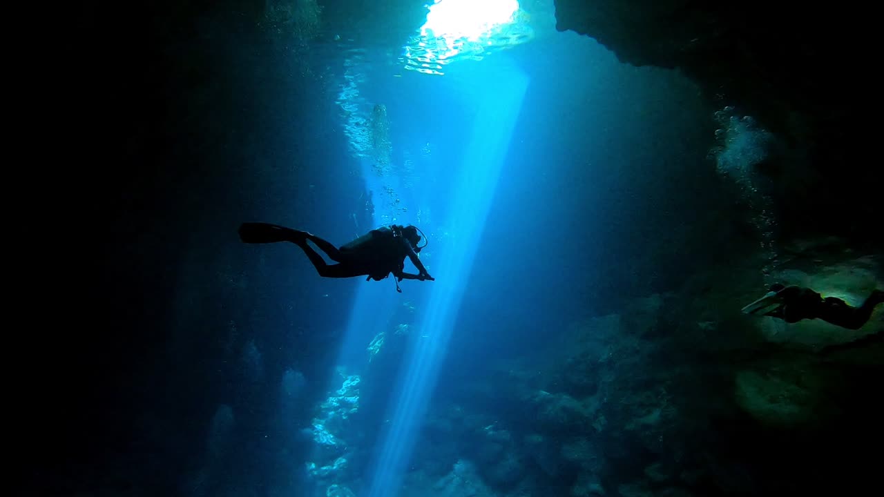 cueva submarina con rayos de sol y silueta de buzo