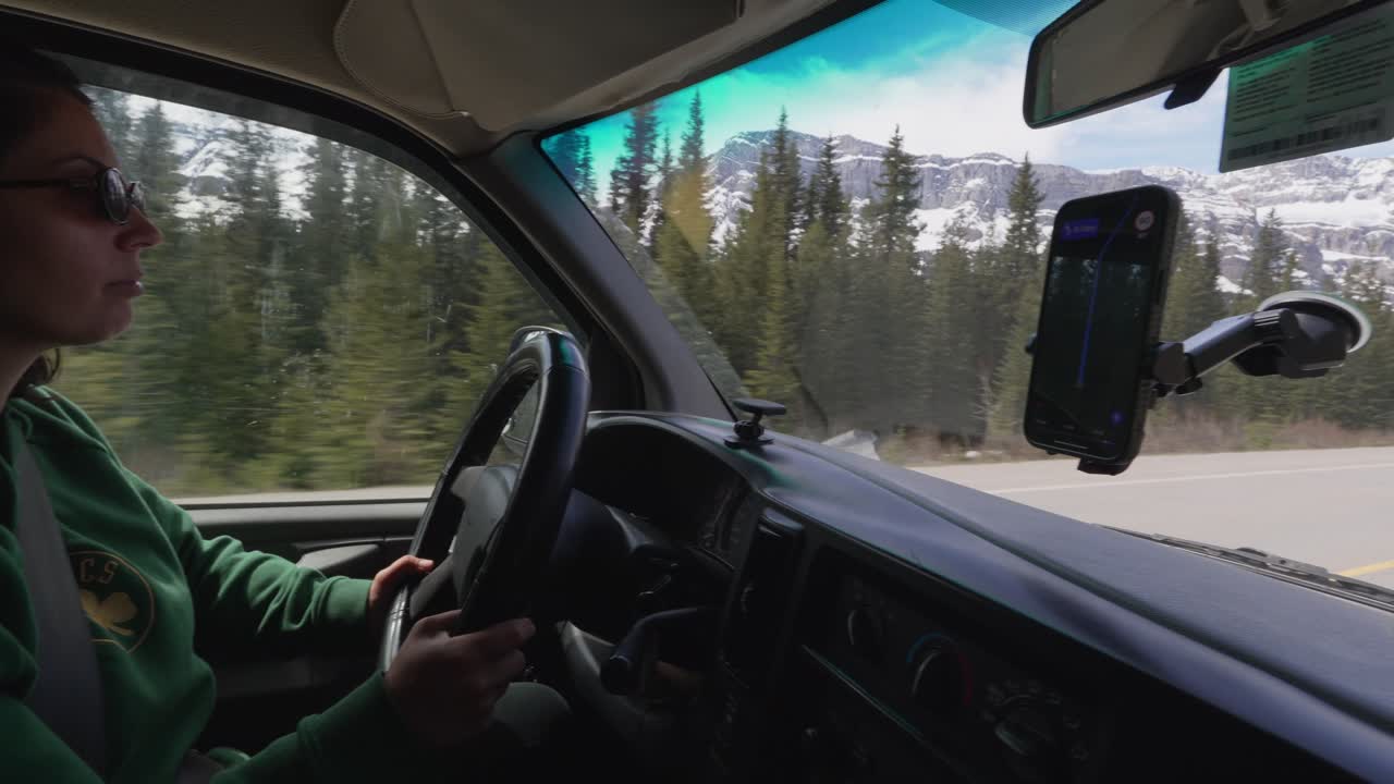 Donna alla guida del suo camper attraverso lo splendido paesaggio montano delle Montagne Rocciose canadesi nel Parco Nazionale di Banff.