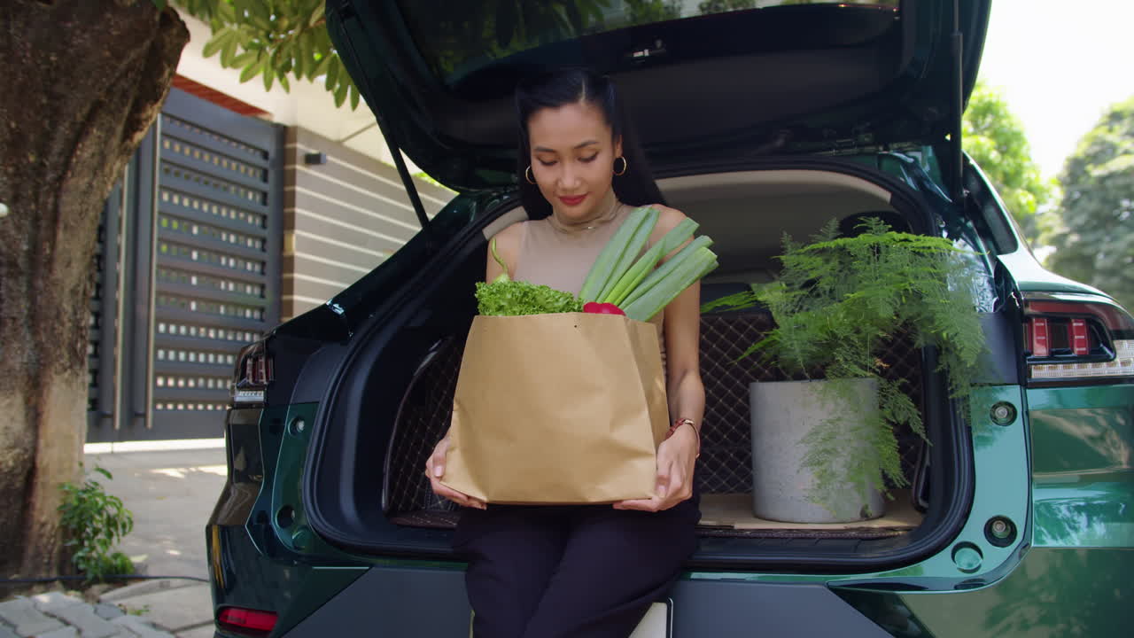 Woman with Groceries in Car Trunk