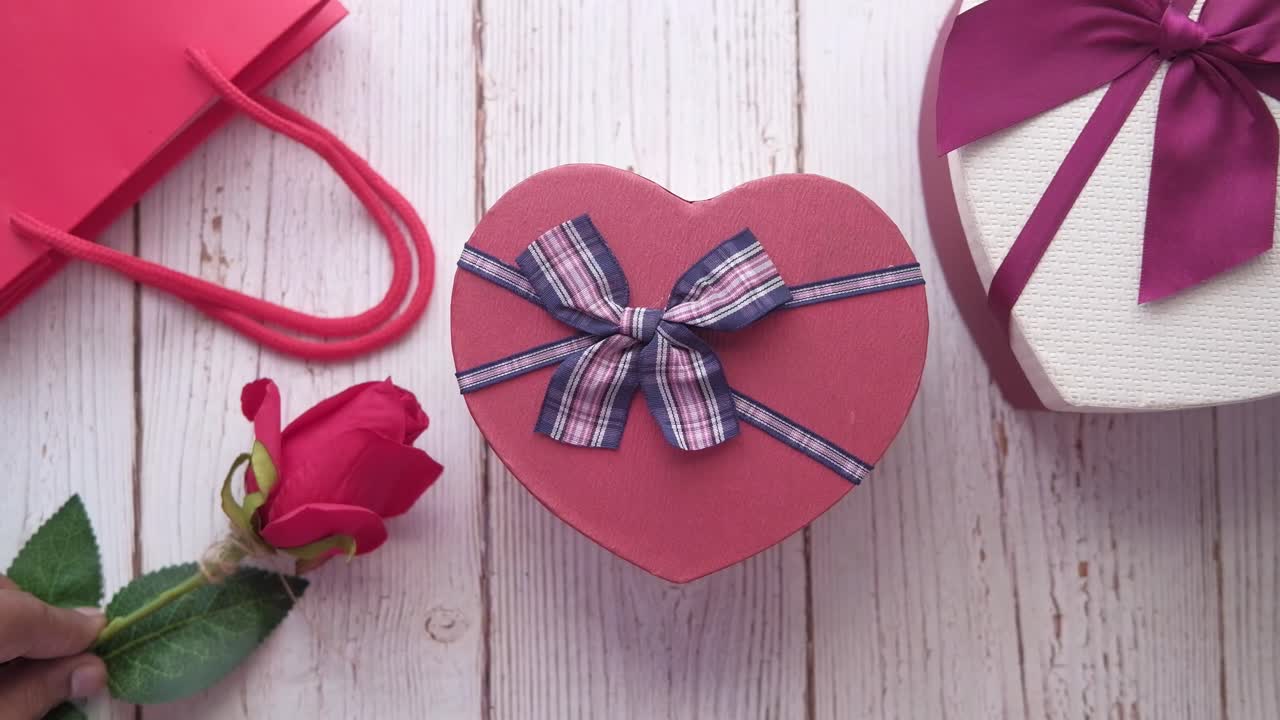 Regalos en forma de corazón y rosas rojas sobre una mesa de madera