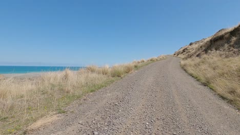 Pov-Ciclismo-Todoterreno-Cuesta-Arriba-Desde-Un-Asentamiento-Junto-Al-Mar-En-Un-Hermoso-Día-De-Verano---Bossu-Road,-Canterbury