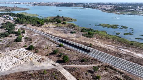 Imágenes-De-Drones-En-Paralelo-Sobre-Los-Vagones-De-Tren-Estacionados-En-Un-Campo-De-Atletismo-Al-Sur-De-Lisboa