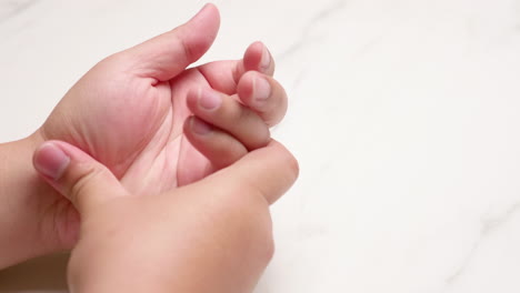 close-up on an individual massaging herself by squeezing and pressing her hands and fingers to relieve the inflammation