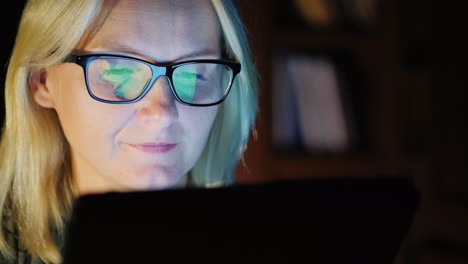 mujer con gafas trabaja en tableta por la noche