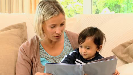 madre joven leyendo un libro para niños al bebé en el regazo
