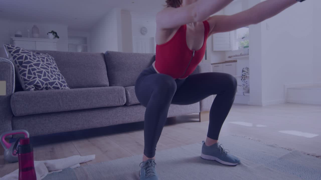 Donna con top rosso che inizia uno squat basso ed esegue ripetizioni per il fitness su un tappetino, mostrando un tracker e dei badge.