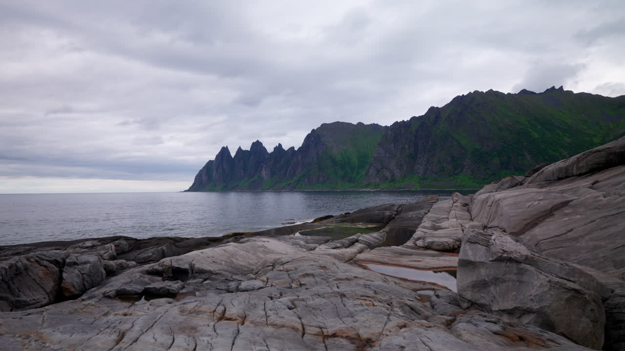 Female tourist walk on rocks with view of Devil's Teeth Okshornan mountain