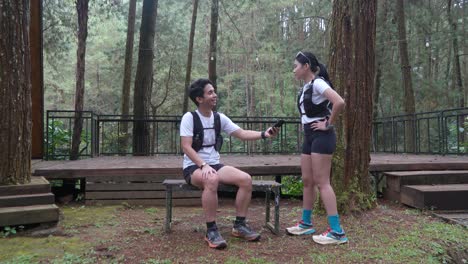 asian couple taking photo with smartphone during outdoor trail run in indonesian forest