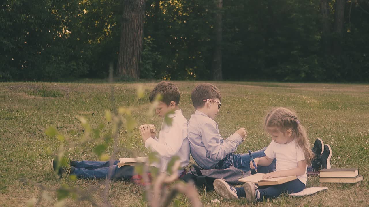 소년 은 반 친구 와 작은 소녀 의  ⁇  에 앉아 샌드위치 를 먹고 있다