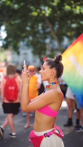 woman at a pride parade taking pictures with her phone