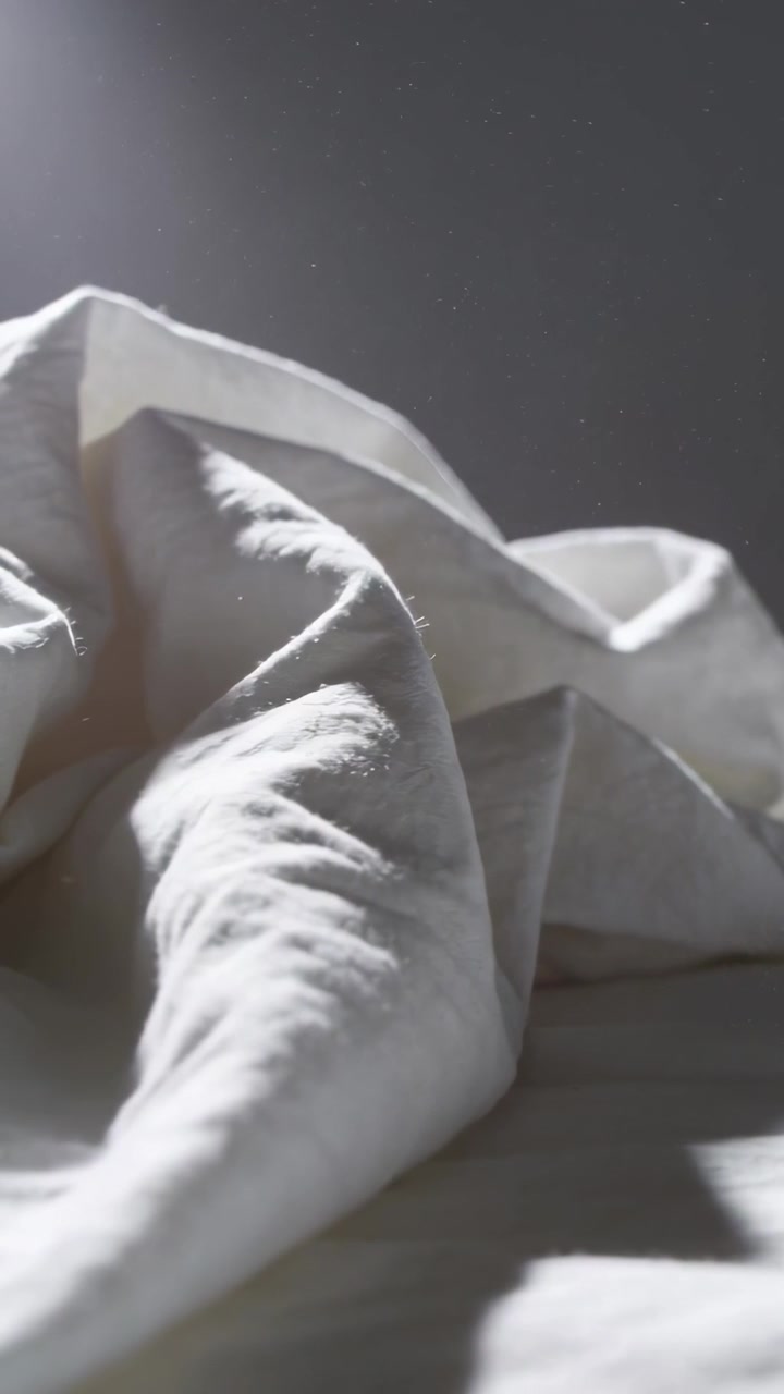 Video verticale: La telecamera si solleva mostrando un piumino bianco che si muove sul letto, rivelando pulviscolo.