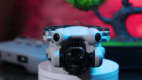 vista frontal del quadcopter, plegado con el controlador en el fondo, con la iluminación azul desvaneciéndose, dji mini 4 pro drone epic shot