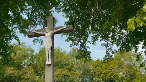 jesus statue hangs on a concrete cross in limburg during spring in a forest