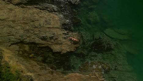 person relaxing on rocks by the ocean