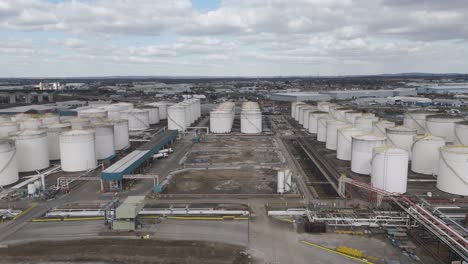 aerial top-down of grid of massive cylindrical gas holders linked by pipelines and access roads, depicting large-scale energy storage infrastructure