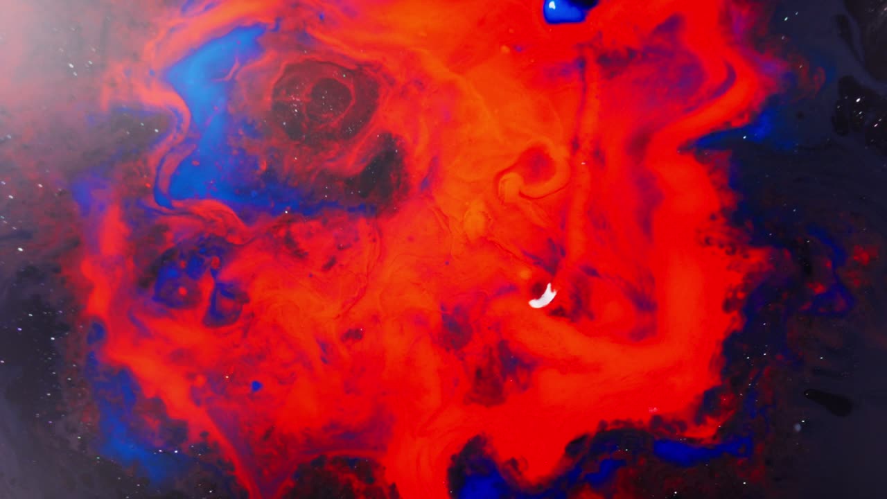 Swirling red and blue alcoholic ink in water creates a dreamy abstract macro view