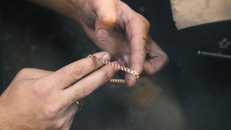 el orfebre muestra un brazalete de oro en la tienda de joyas de cerca