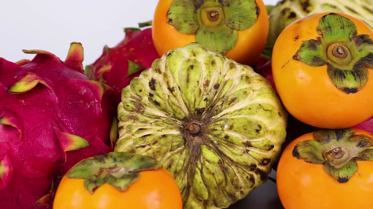 A colorful arrangement featuring dragon fruit and persimmons, highlighting their vibrant textures and natural beauty.