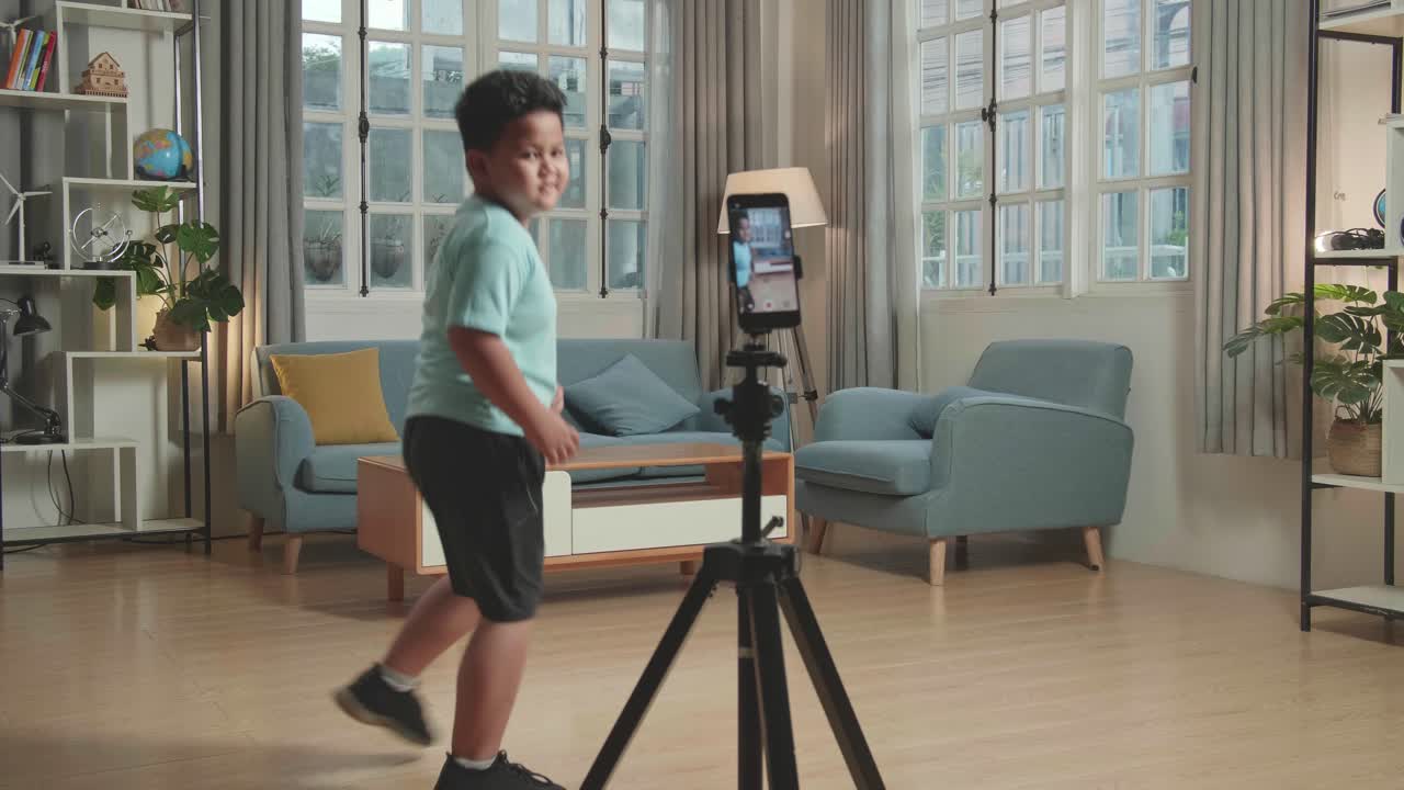Asian Little Boy Dancing While Shooting Video Content For Social Networks With A Smartphone Camera