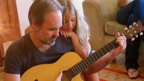 a father and daughter play guitar together in their living room at home