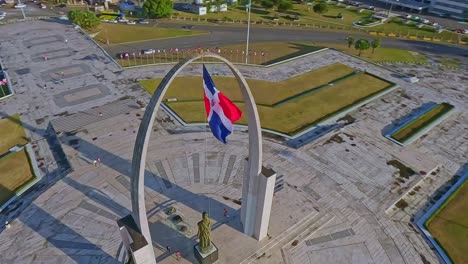 drone flying around triumphal arch in plaza de la bandera with cityscape, santo domingo in dominican republic